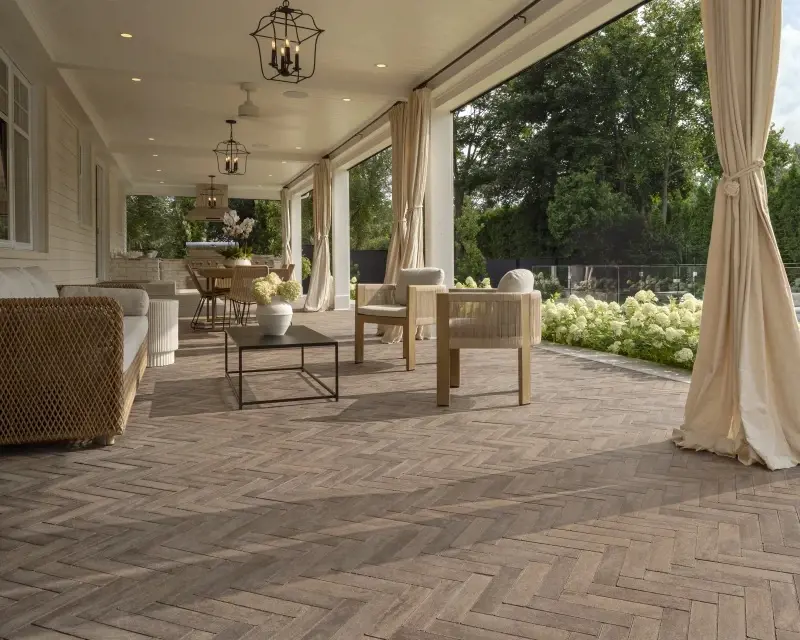 Patio couvert élégant en pavés Westmount de Techo-Bloc, disposés en motif chevron, créant un espace de vie extérieur chaleureux, structuré et intemporel.