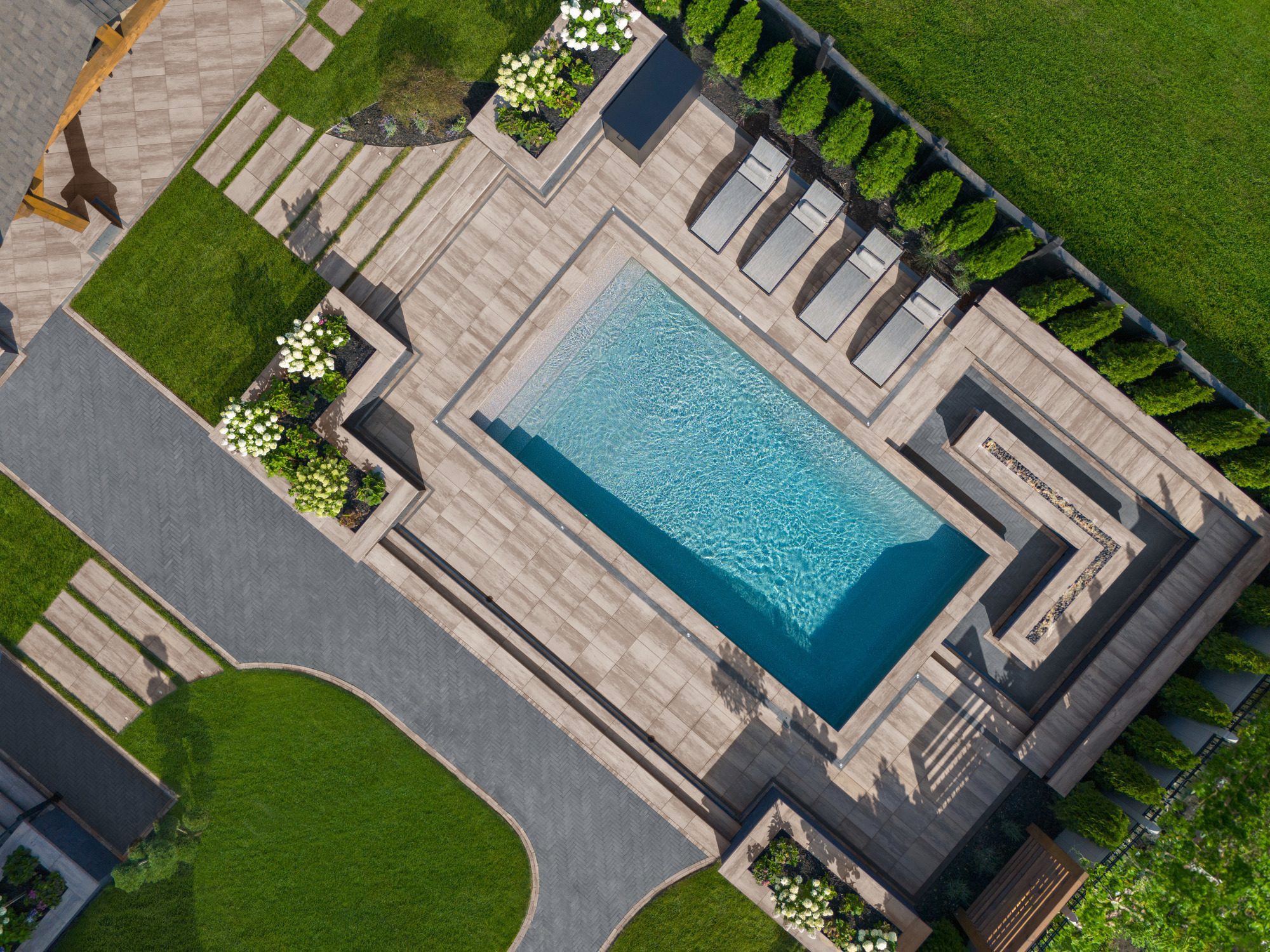 Overhead view of the renovated backyard featuring a pool, lounge area, landscaping, and expanded modern hardscaping.