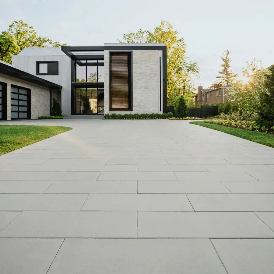 Industria Smooth Paver by Techo-Bloc in Silver Granite with smooth texture, creating a sleek patio for outdoor dining beside a modern brick building.