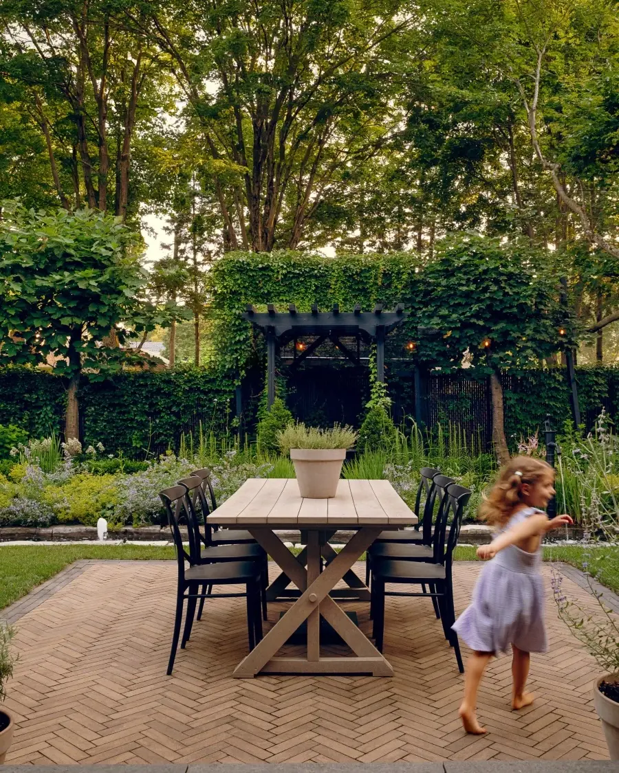 Outdoor dining area surrounded by mature trees, featuring Westmount cobblestone style pavers in Chestnut Brown that blend naturally with the landscape.
