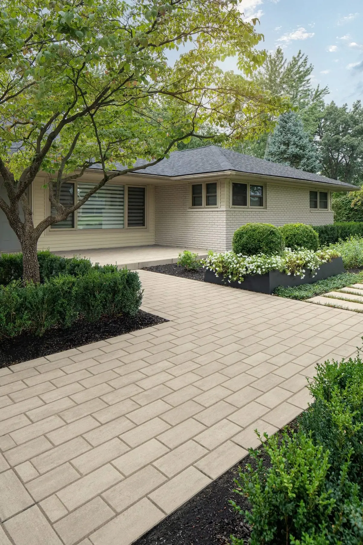 Neutral-toned patio with warm stone-texture Techo-Bloc slabs and soft landscaping for a timeless aesthetic.