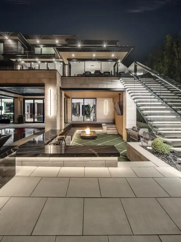 Cour arrière conçue pour l’art de recevoir en plein air, avec paliers modernes, foyer encastré et ambiance lumineuse chaleureuse.