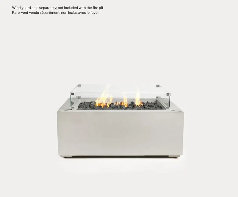 Sculptura Firepit Square by Techo-Bloc, featuring a modern concrete design with black lava stones and a clear glass barrier surrounding the flickering flames. Disclaimer the Wind Guard is not included.