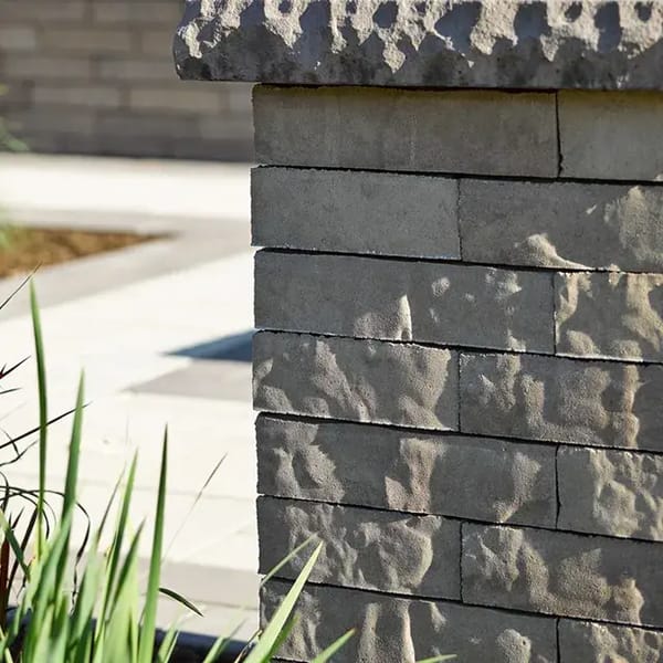 Brandon by Techo-Bloc, rustic double-sided retaining wall blocks with a dry-stacked appearance, creating a sturdy and textured boundary for outdoor spaces.