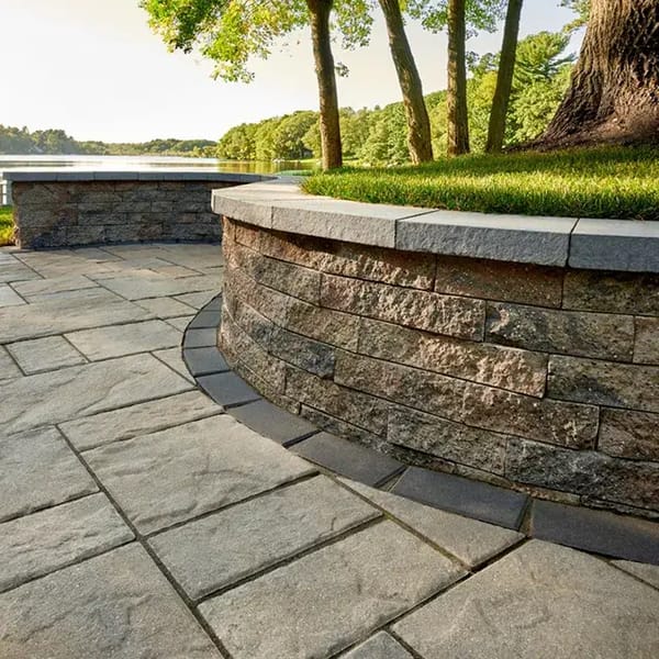  Mini-Creta Architectural by Techo-Bloc, concrete retaining wall blocks with clean edges, forming a curved wall along a patio for added structure and elegance.