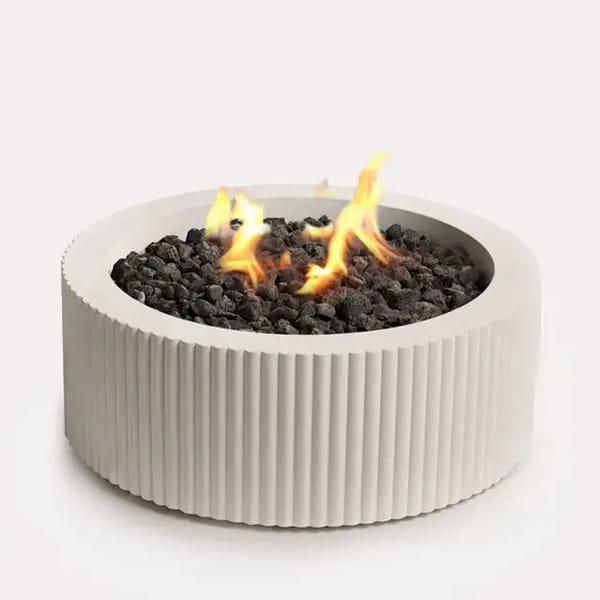 Sculptura Fire Pit Scalloped by Techo-Bloc, scalloped circular fire pit with lava rock, adding a unique, stylish feature to your outdoor space.
